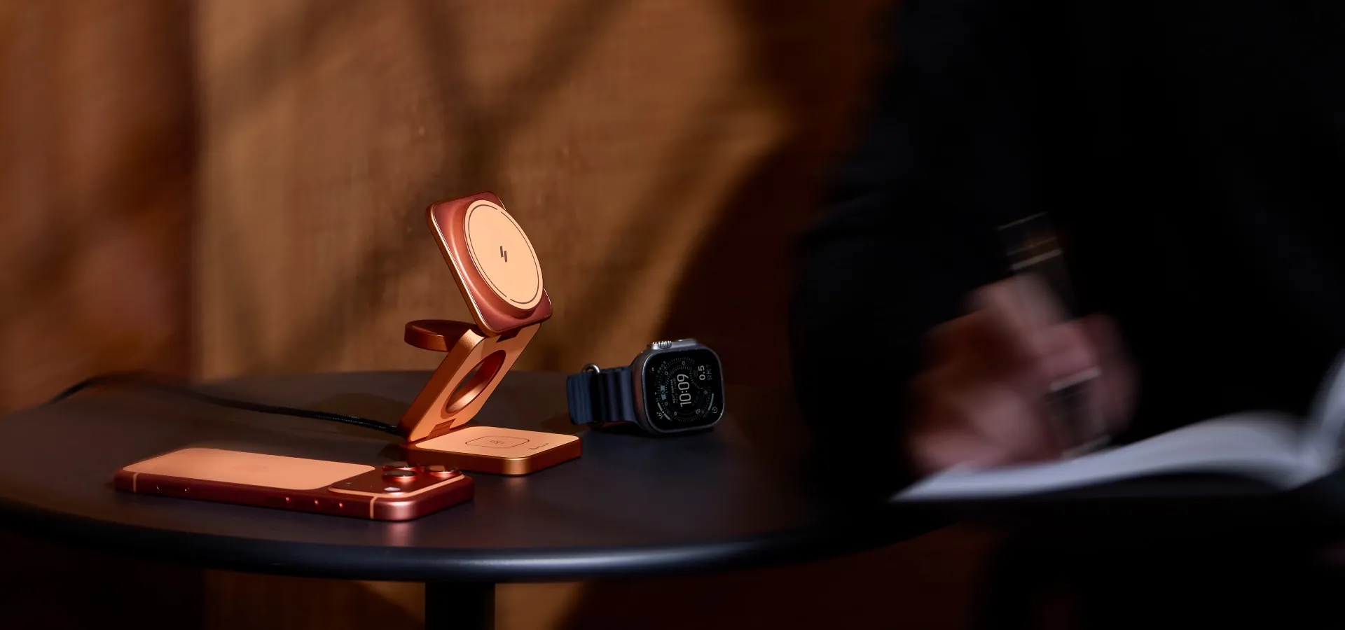 銅色 ADAM Mag 3 Ultra 三合一摺疊充電器與 iPhone、Apple Watch 放在桌上
