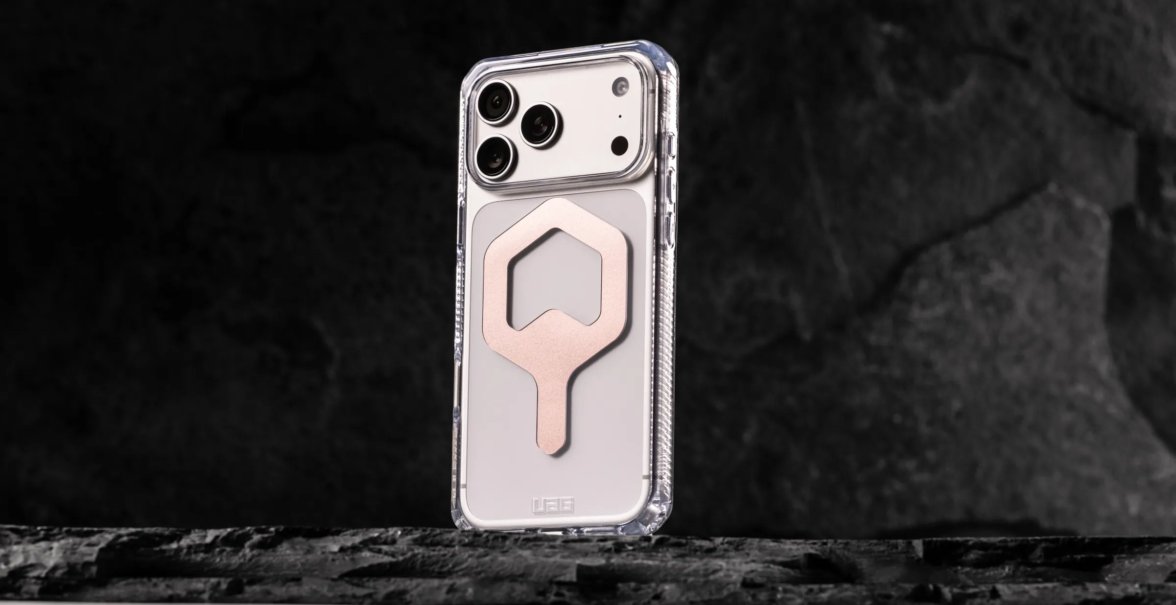 透明 UAG Plyo MagSafe 保護殼立在黑色岩石上